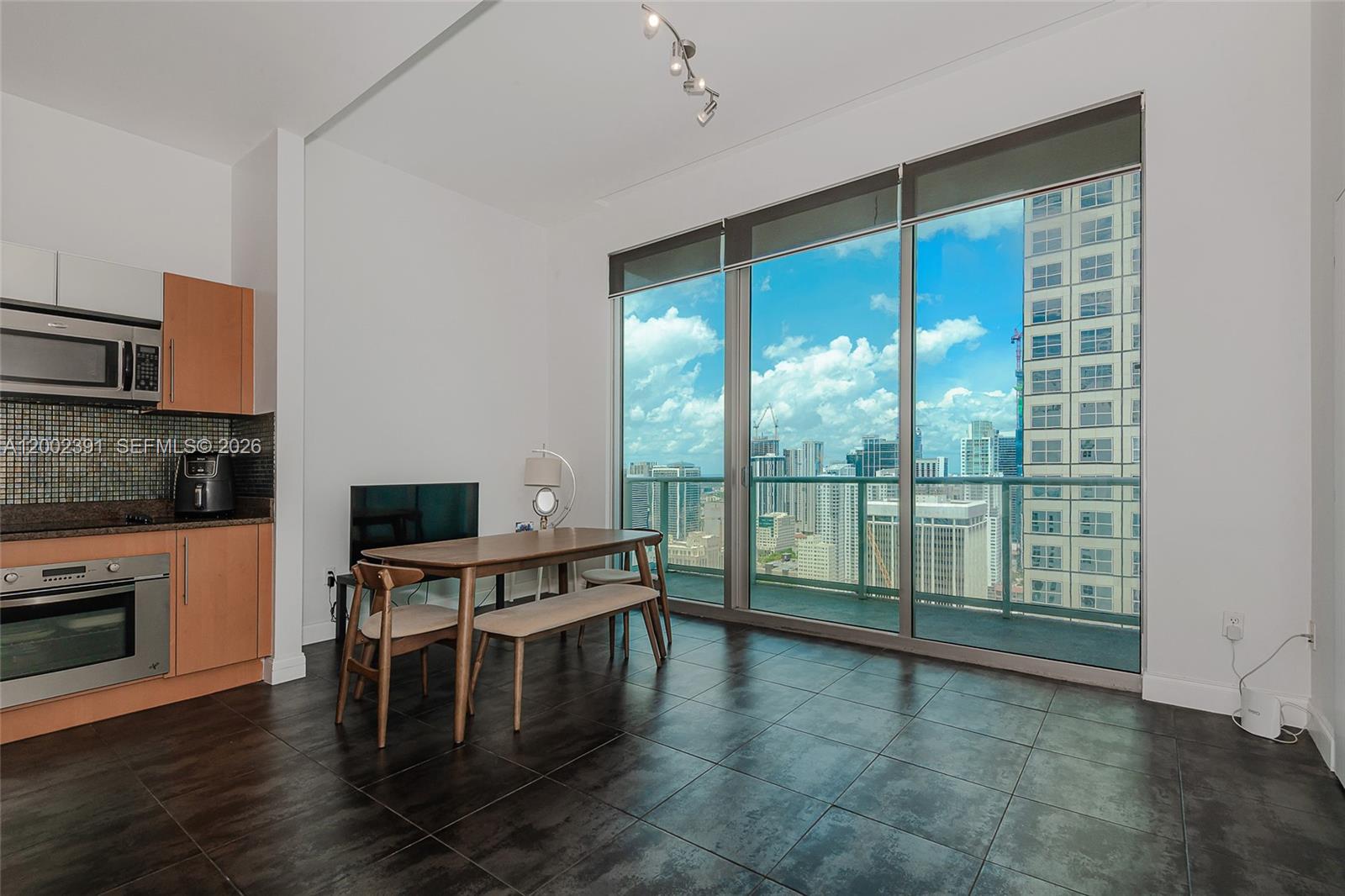 A kitchen and dining area with dark tile floors and floor-to-ceiling windows overlooking a city — 300 S Biscayne Blvd # 3903, Miami FL 33131, MIAMI, FL