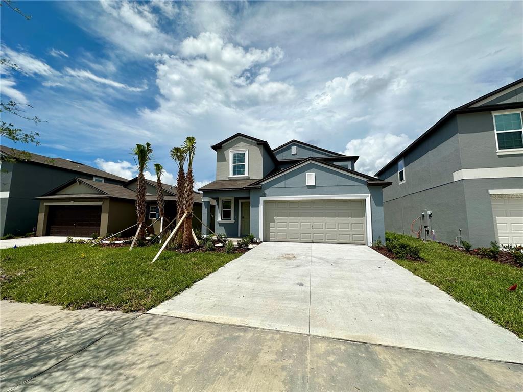 A two-story suburban house with a blue exterior, a two-car garage, and a concrete driveway — 11131 RADIANT SHORE LOOP, SAN ANTONIO, FL