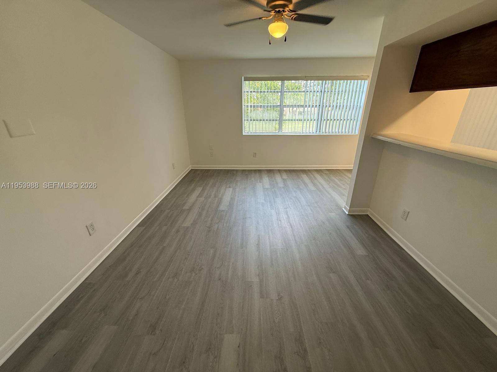 An unfurnished room features light gray wood-look flooring, white walls, a ceiling fan, and a window — 15285 SW 107th Ln # 214, Miami FL 33196, MIAMI, FL