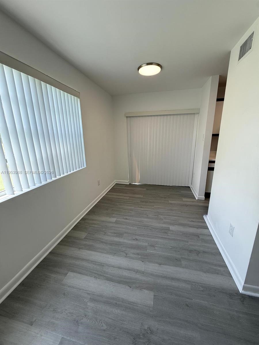This room features gray wood-look flooring, white walls, and vertical blinds on the windows — 15285 SW 107th Ln # 214, Miami FL 33196, MIAMI, FL