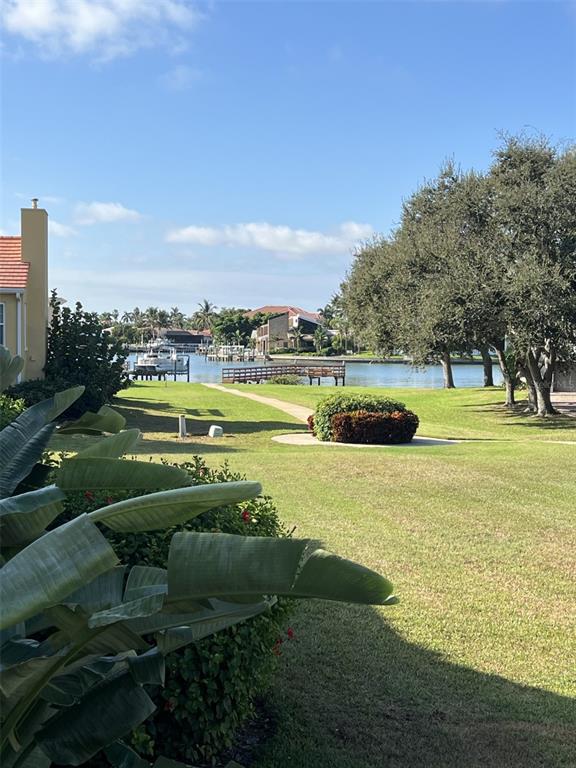 A view of a grassy lawn leading to a canal with a wooden dock — 18 JEFFERSON COURT S, ST PETERSBURG, FL