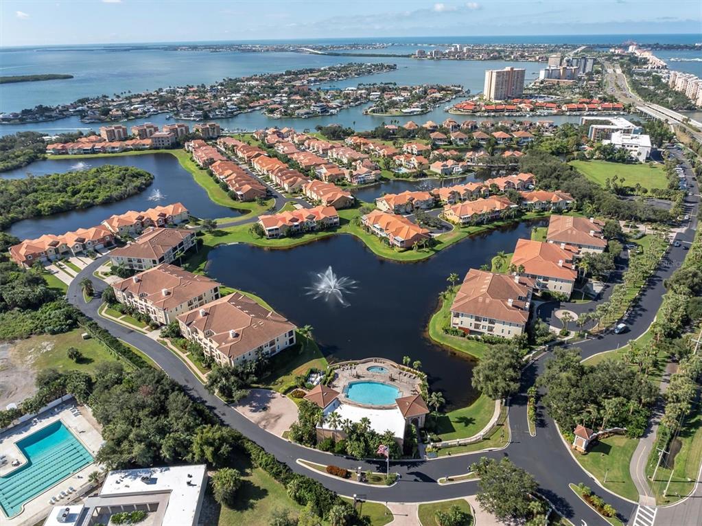 An aerial view shows a residential complex with a central pond, fountain, and swimming pools — 18 JEFFERSON COURT S, ST PETERSBURG, FL