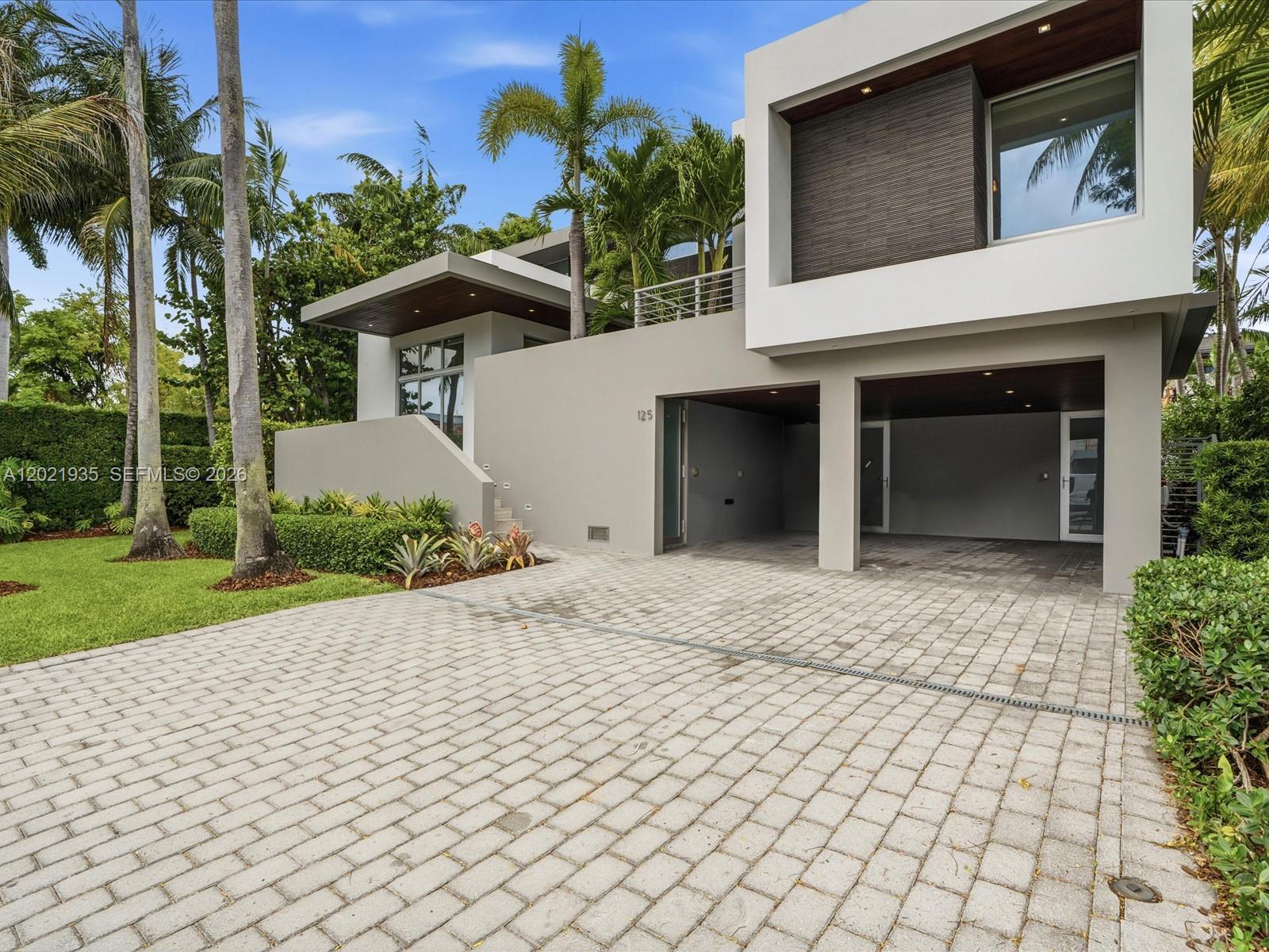 A modern two-story house features a paved driveway, a two-car garage, and tropical landscaping — 125 Hampton Ln, Key Biscayne FL 33149, KEY BISCAYNE, FL