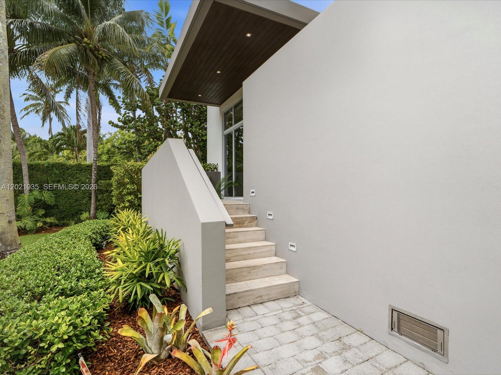 A concrete staircase with a side wall leads to a glass door under a roof — 125 Hampton Ln, Key Biscayne FL 33149, KEY BISCAYNE, FL