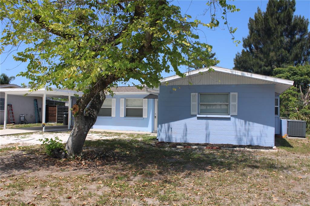 A light blue, single-story house features a white carport and a large tree in front — 3316 W 26TH STREET, BRADENTON, FL