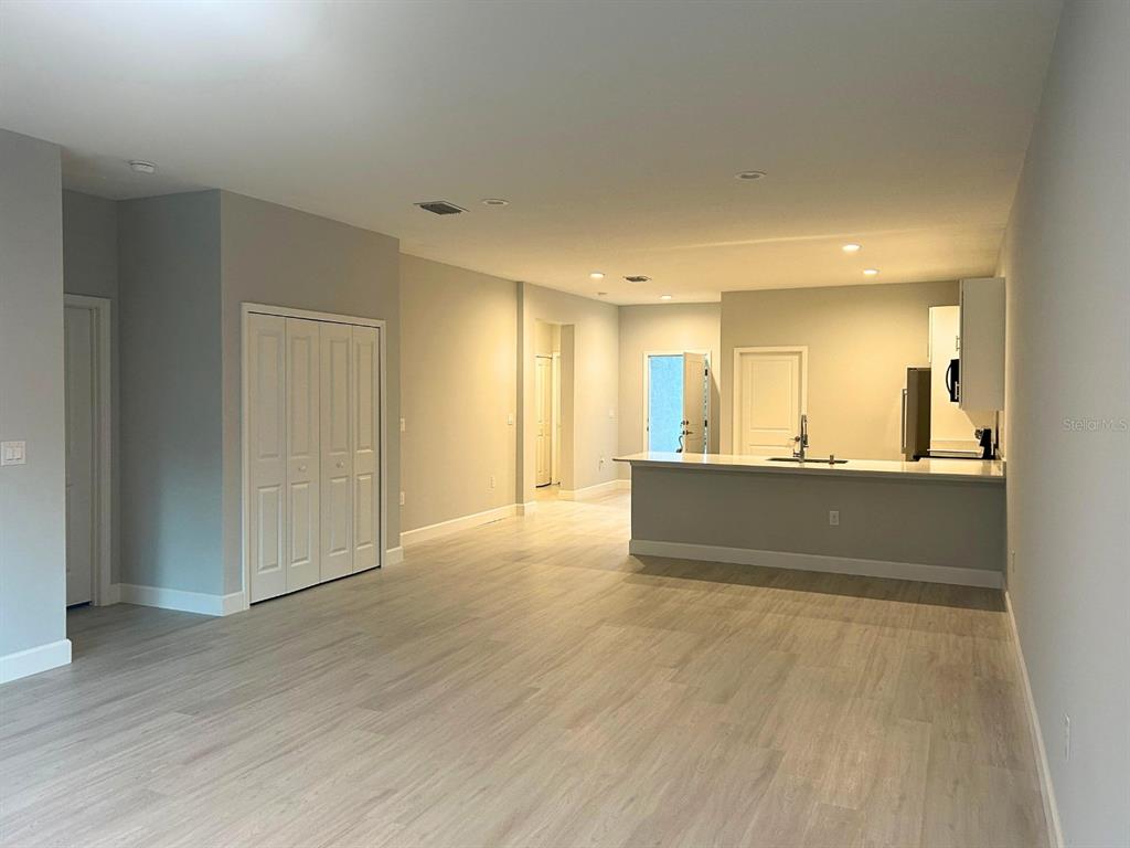 An open-concept living area features light wood-look flooring, a kitchen island, and white cabinetry — 10385 PORT EVERGLADES STREET, PORT CHARLOTTE, FL
