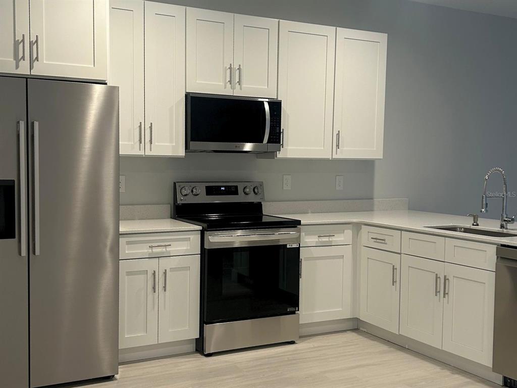 A kitchen features white shaker cabinets, stainless steel appliances, and light-colored quartz countertops — 10385 PORT EVERGLADES STREET, PORT CHARLOTTE, FL