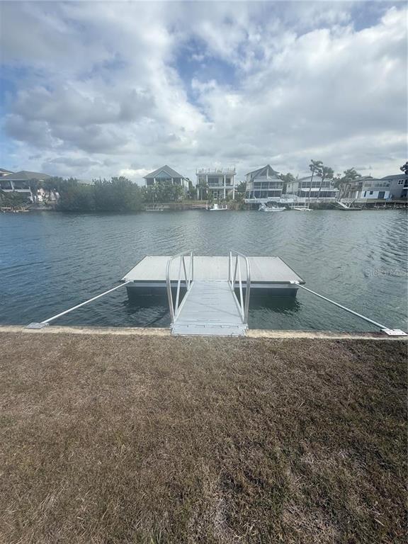 A floating dock with a metal gangway extends from a grassy lawn into a canal — 3220 AZALEA DRIVE, HERNANDO BEACH, FL