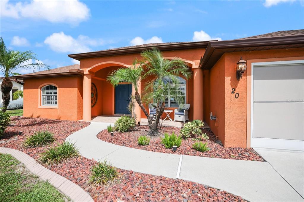 An orange house exterior features a covered entryway, a palm tree, and a concrete walkway — 20 CORY STREET, PORT CHARLOTTE, FL