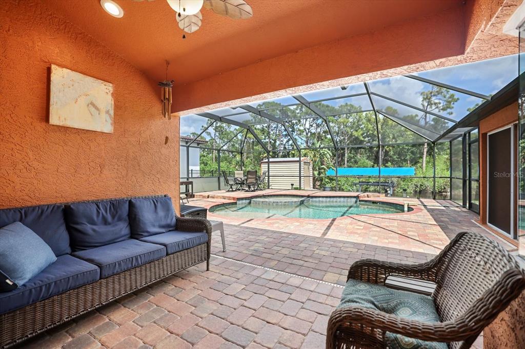 A covered patio with a wicker sofa and chair overlooks a screened-in pool area — 20 CORY STREET, PORT CHARLOTTE, FL