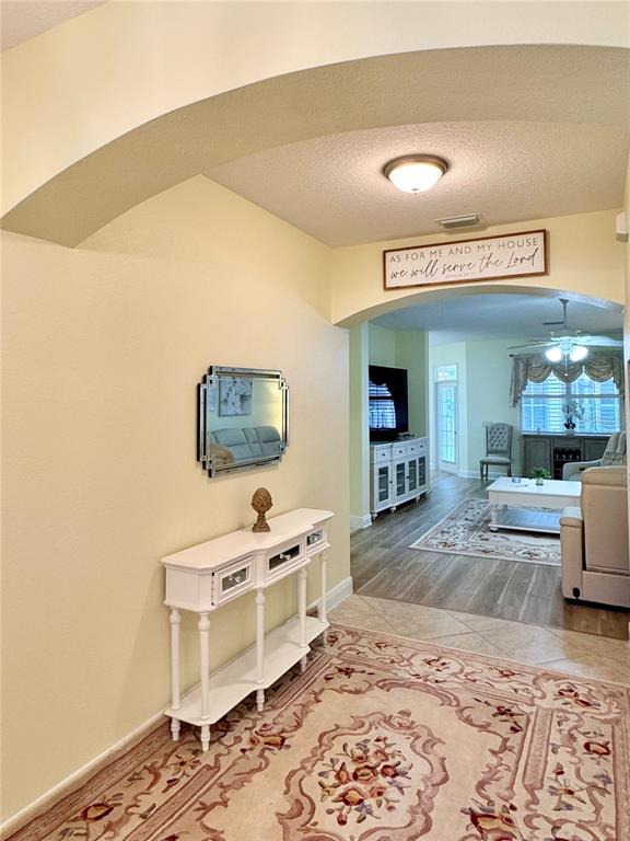 An entryway with a white console table and mirror leads into a living room area — 646 MURPHYS ESTATE DRIVE, THE VILLAGES, FL