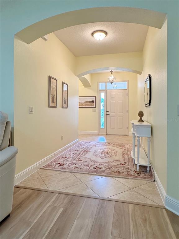 An entryway features a tiled floor with an area rug, arched ceilings, and a white console — 646 MURPHYS ESTATE DRIVE, THE VILLAGES, FL