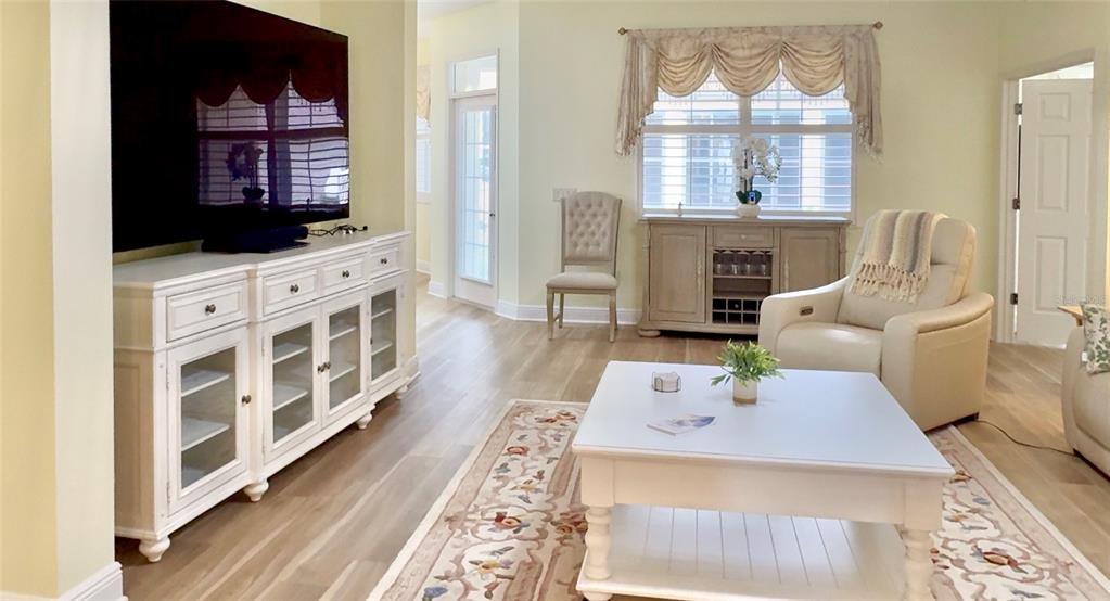 A living room features a white media console, a coffee table, and a beige armchair — 646 MURPHYS ESTATE DRIVE, THE VILLAGES, FL