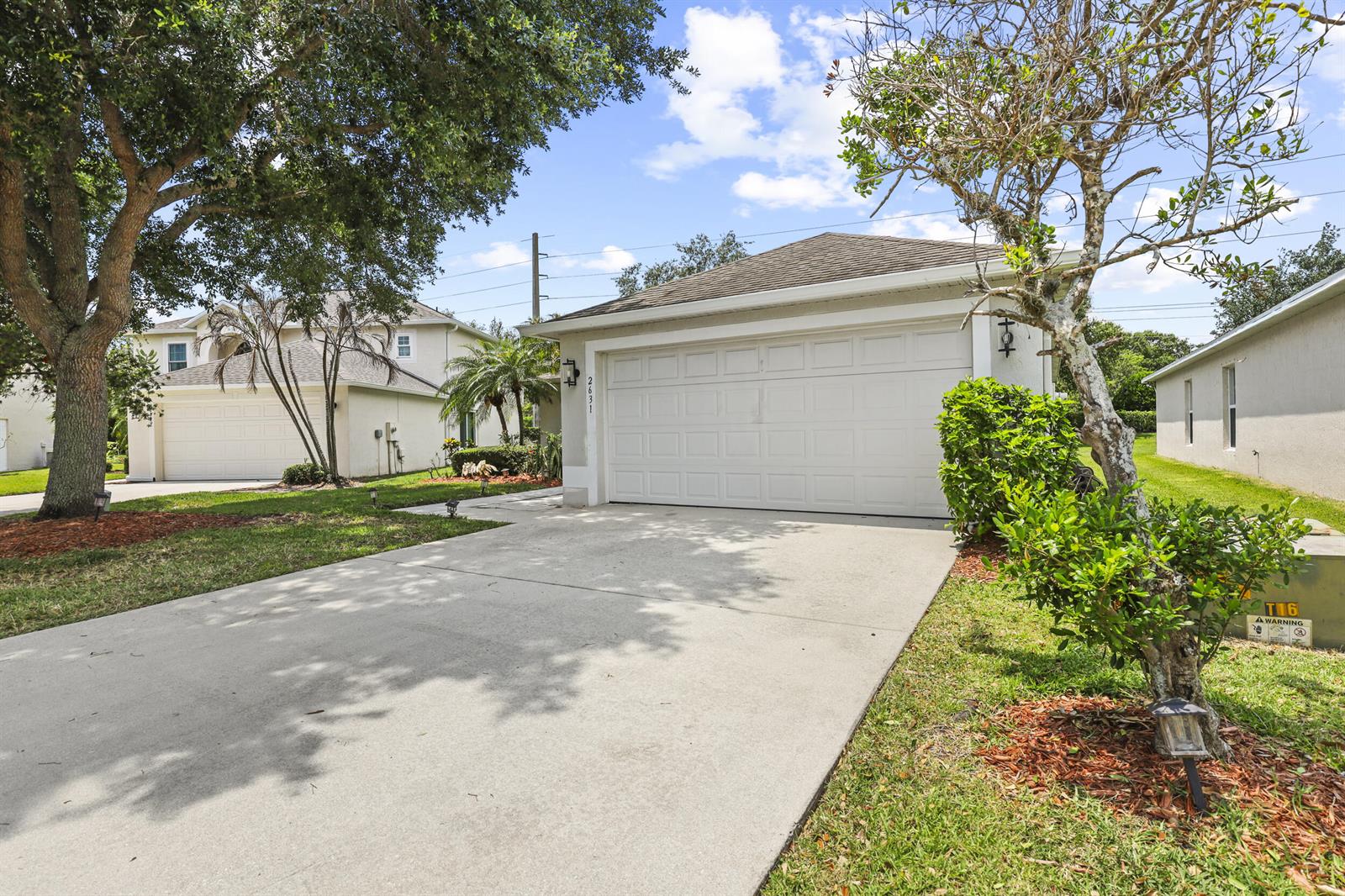 A concrete driveway leads to the two-car garage of a single-story suburban house — 2631 12th Square SW, Vero Beach FL 32968, VERO BEACH, FL