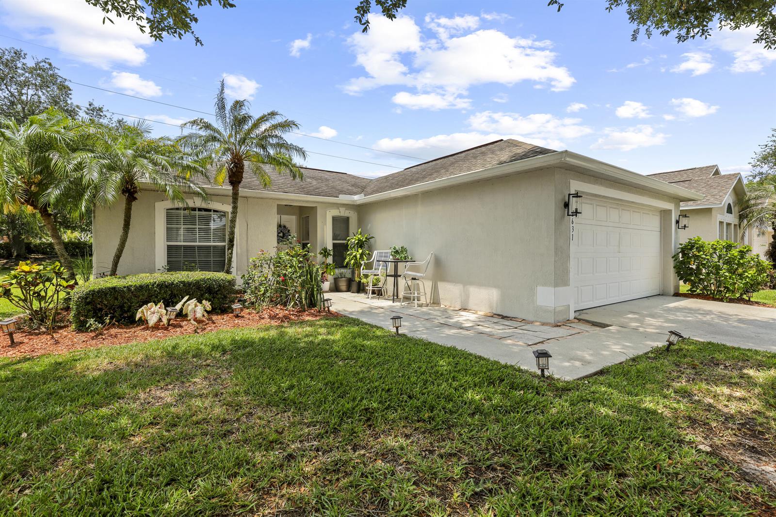 A single-story house with a white garage, a small patio, and palm trees in front — 2631 12th Square SW, Vero Beach FL 32968, VERO BEACH, FL