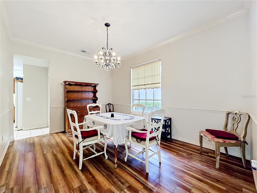 A dining room features wood-look flooring, a crystal chandelier, a hutch, and a table set — 1838 SENECA BLVD, WINTER SPRINGS, FL