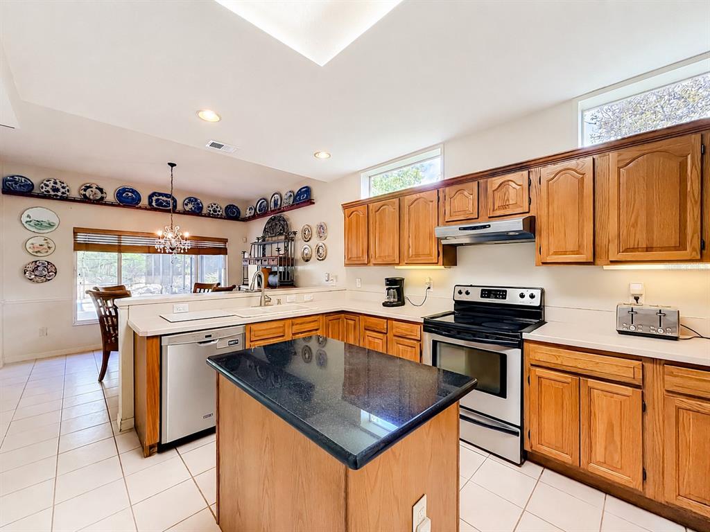 A kitchen features oak cabinets, black granite countertops, a central island, and tiled flooring — 1838 SENECA BLVD, WINTER SPRINGS, FL