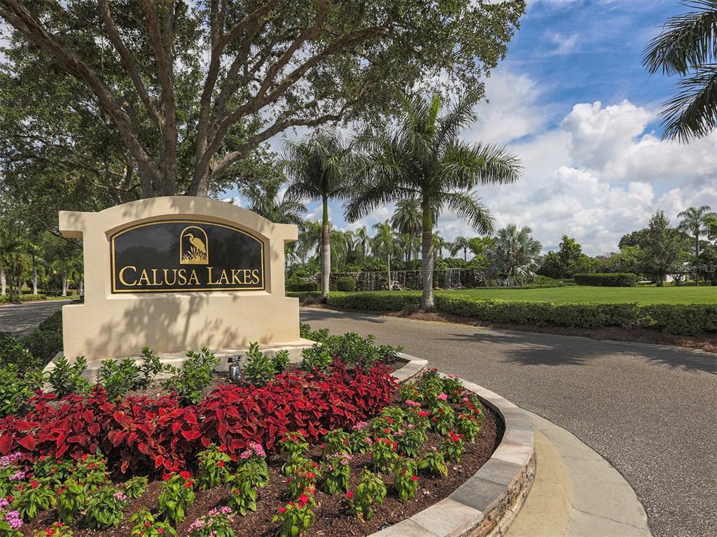 A stone monument sign for Calusa Lakes sits in a landscaped garden by a road — 2139 CALUSA LAKES BOULEVARD, NOKOMIS, FL
