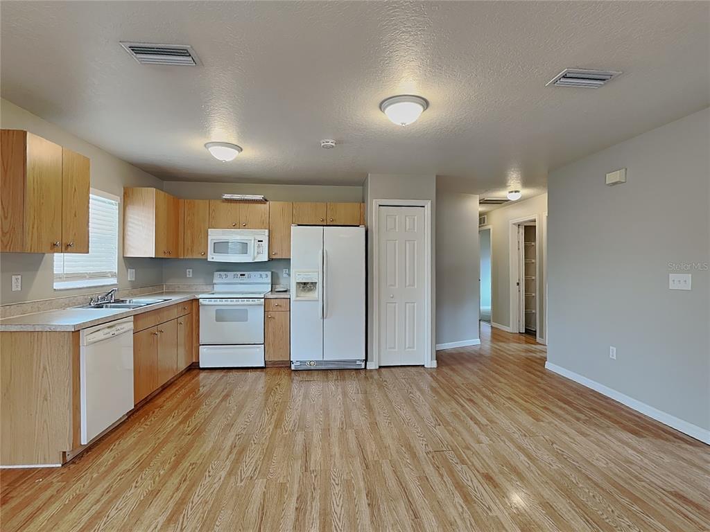 A kitchen features light wood cabinets, white appliances, and wood-look flooring — 2835 31ST AVENUE E, BRADENTON, FL