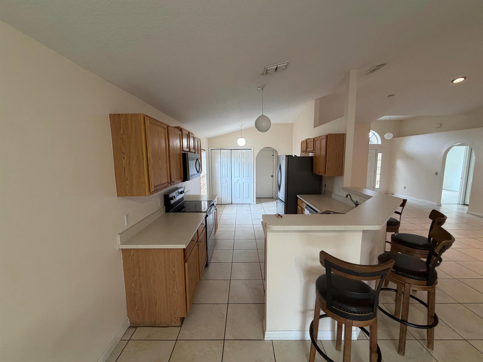 A kitchen features oak cabinets, white countertops, tile flooring, and a breakfast bar with stools — 3426 NW 38th Avenue # 3426, Okeechobee FL 34972, OKEECHOBEE, FL