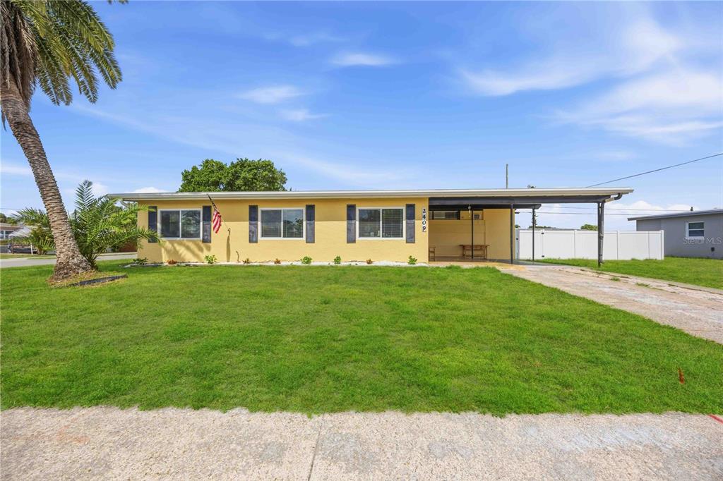 A single-story yellow house with a carport and a palm tree in the front yard — 2409 EDNOR STREET, PORT CHARLOTTE, FL
