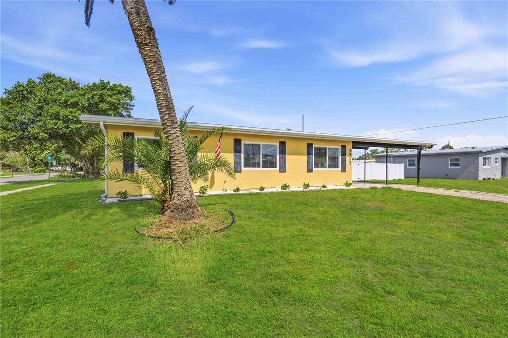 A yellow single-story house with a palm tree in the front yard and a carport — 2409 EDNOR STREET, PORT CHARLOTTE, FL