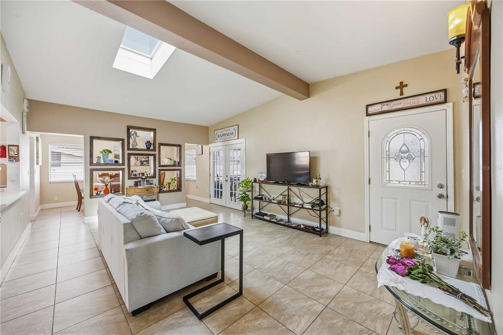 A living room features tile floors, a vaulted ceiling with a skylight, and a front door — 2409 EDNOR STREET, PORT CHARLOTTE, FL