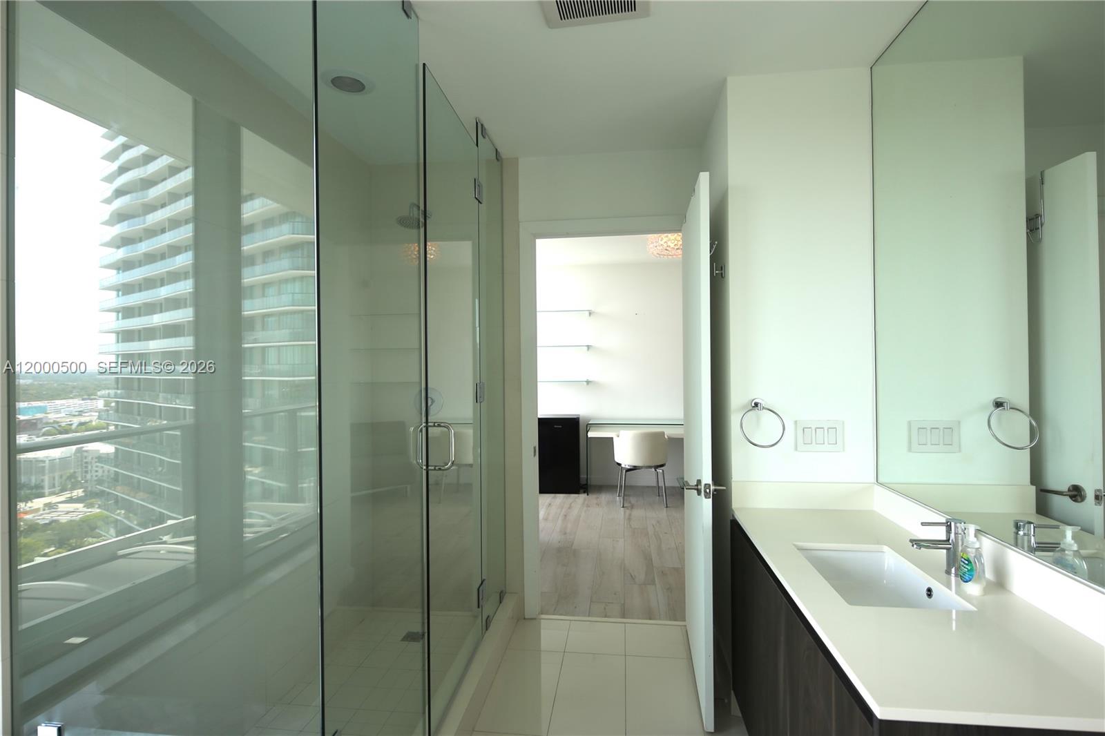 A modern bathroom features a glass-enclosed shower, a vanity with a sink, and a doorway — 480 NE 31 St # 2607, Miami FL 33137, MIAMI, FL
