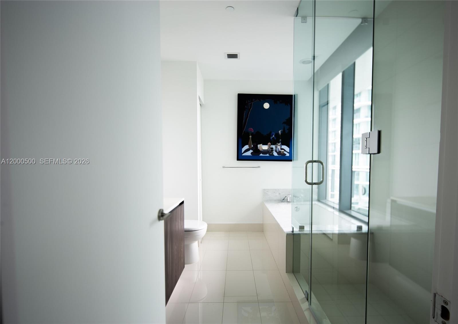 A modern bathroom features a glass-enclosed shower, a soaking tub, and a dark framed painting — 480 NE 31 St # 2607, Miami FL 33137, MIAMI, FL