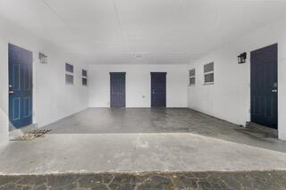 A covered carport with a concrete floor and four dark blue doors on white walls — 508 NE 12th Avenue, Pompano Beach FL 33060, POMPANO BEACH, FL