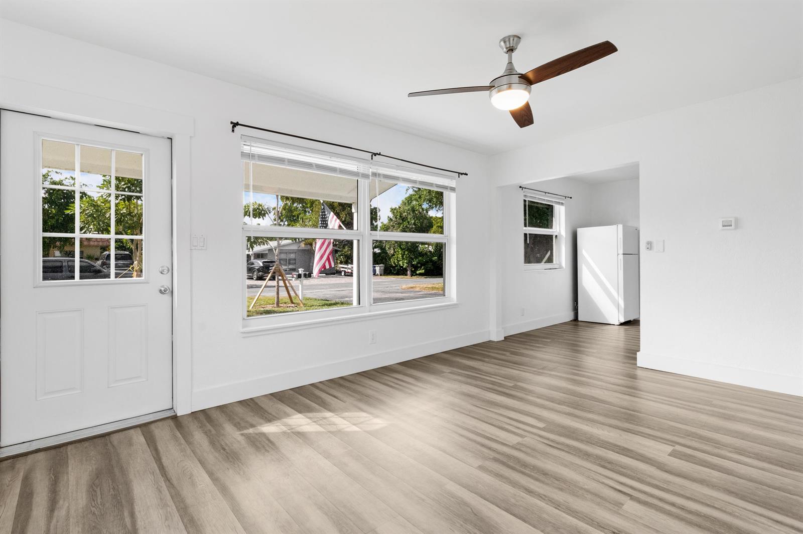 A bright room features light wood-look flooring, white walls, a ceiling fan, and large windows — 508 NE 12th Avenue, Pompano Beach FL 33060, POMPANO BEACH, FL