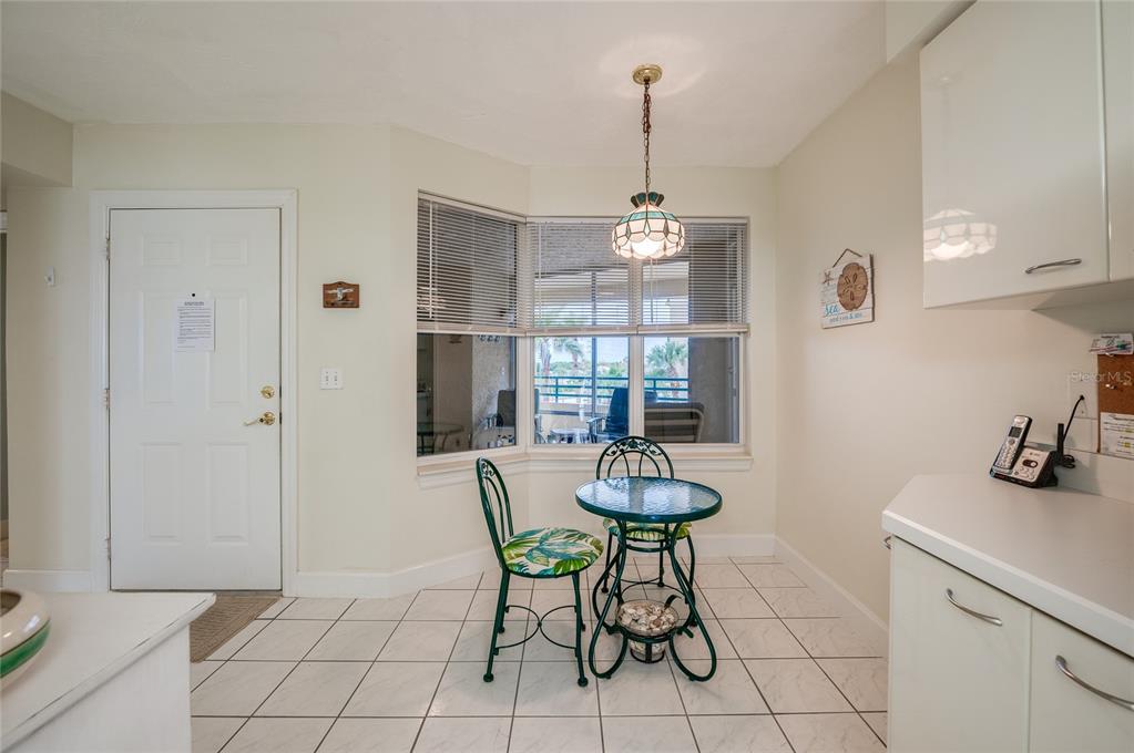 A breakfast nook features a small glass table, two chairs, tile flooring, and a bay window — 4575 S ATLANTIC AVENUE UNIT 6310, PORT ORANGE, FL