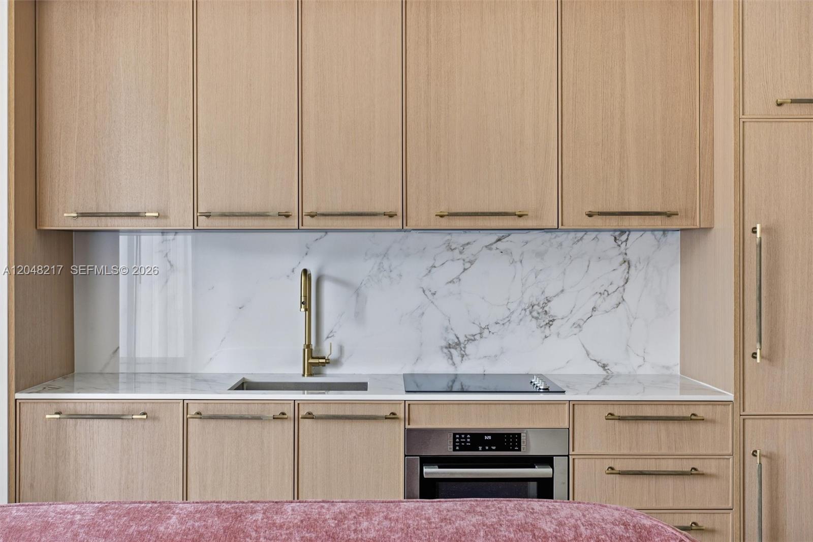 A modern kitchen features light wood cabinets, a marble backsplash, and a gold faucet — 2700 NW 2nd Ave # 432, Miami FL 33127, MIAMI, FL