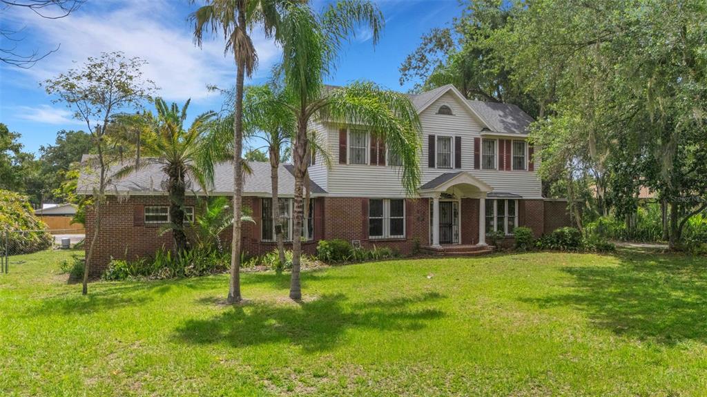 A two-story house with a brick lower level and white siding, surrounded by trees — 820 S OAK AVENUE, BARTOW, FL