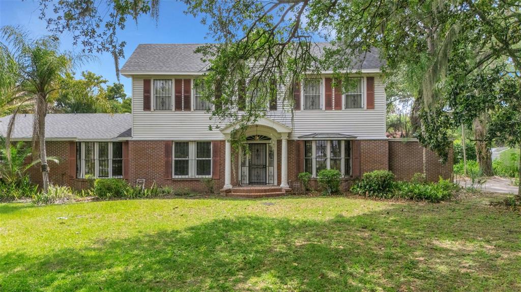 A two-story house with a brick and siding exterior features a central columned entryway — 820 S OAK AVENUE, BARTOW, FL