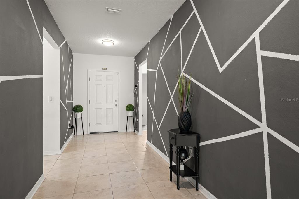 A hallway features tile flooring and walls painted dark gray with white geometric accent lines — 13120 CONQUISTADOR LOOP, SPRING HILL, FL