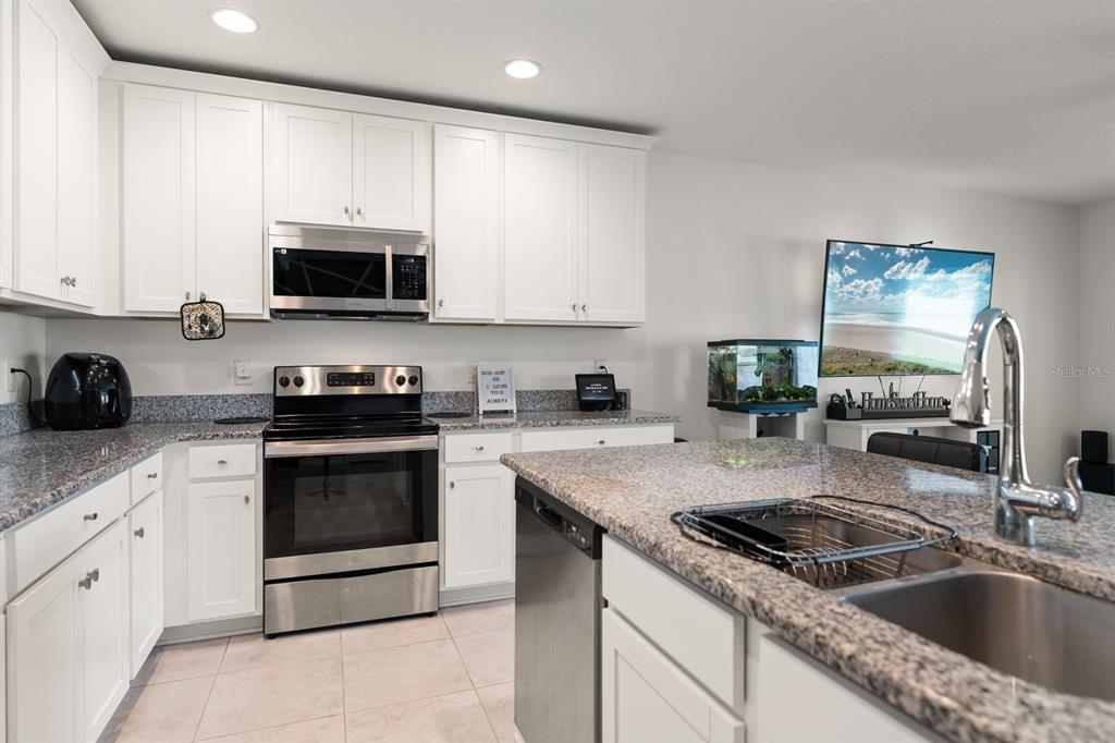 A kitchen with white cabinets, granite countertops, stainless steel appliances, and a central island — 13120 CONQUISTADOR LOOP, SPRING HILL, FL