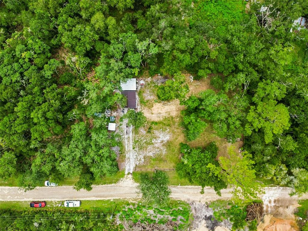 An aerial view shows a small house surrounded by dense trees and a dirt driveway — 35314 GOETHALS STREET, WEBSTER, FL