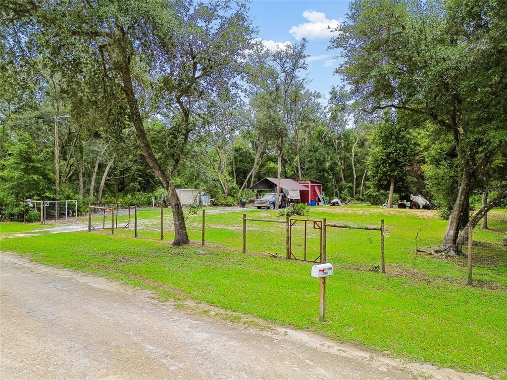 A gravel road leads to a fenced grassy lot with a shed and parked vehicles — 35314 GOETHALS STREET, WEBSTER, FL
