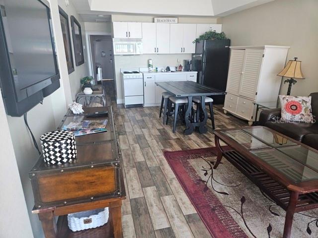 This open-concept living area features a kitchen, dining table, and seating area with wood flooring — 1909 S ATLANTIC AVENUE UNIT 102, DAYTONA BEACH, FL