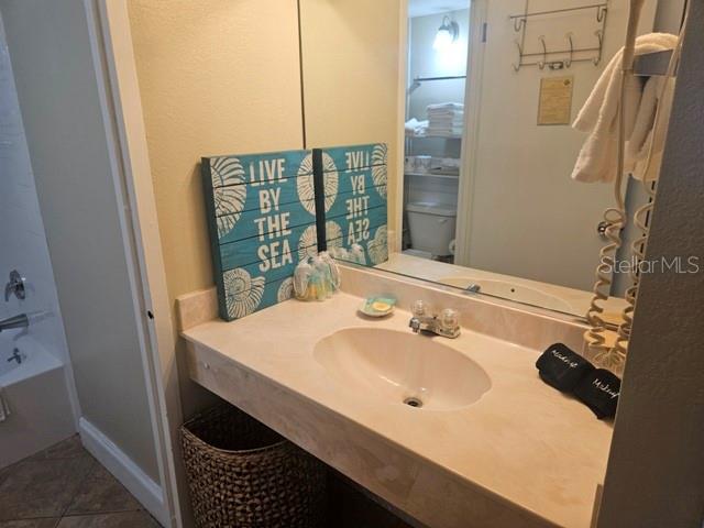 A bathroom features a vanity with a sink, a mirror, and coastal-themed wall art — 1909 S ATLANTIC AVENUE UNIT 102, DAYTONA BEACH, FL