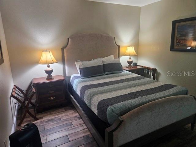 A bedroom features a bed with a light-colored headboard, two nightstands, and wood-look flooring — 1909 S ATLANTIC AVENUE UNIT 102, DAYTONA BEACH, FL
