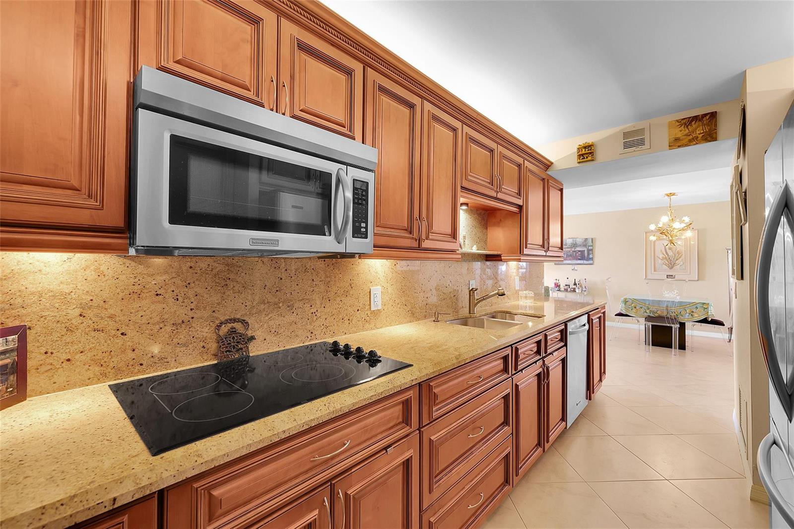 A kitchen with wood cabinets, granite countertops, a glass cooktop, and a stainless steel microwave — 1200 Hibiscus Avenue, Pompano Beach FL 33062, POMPANO BEACH, FL