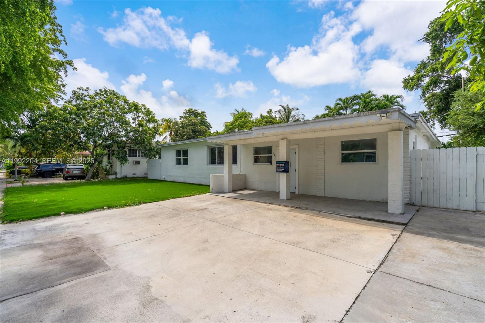 A white single-story house features a concrete driveway, a covered porch, and a green lawn — 181 NE 121st St, North Miami FL 33161, NORTH MIAMI, FL