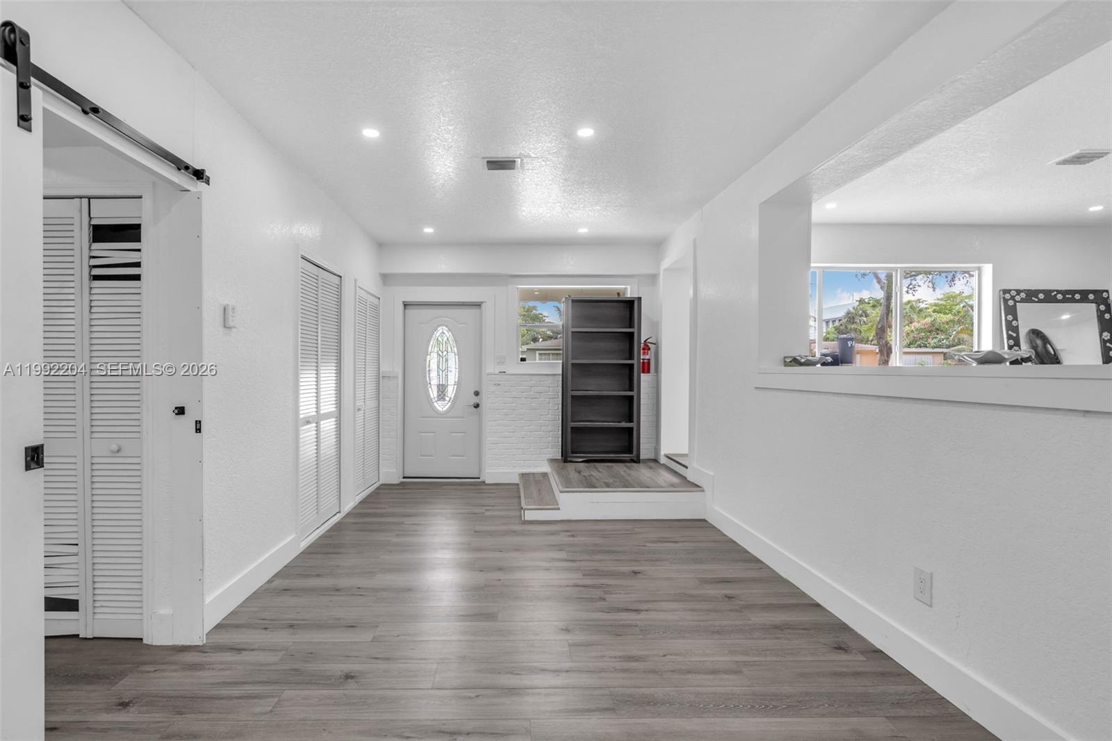An interior room features white walls, gray wood-look flooring, a raised platform, and a doorway — 181 NE 121st St, North Miami FL 33161, NORTH MIAMI, FL