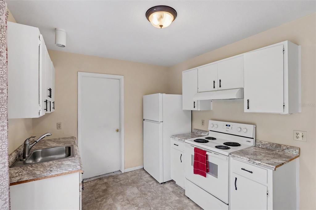 A kitchen with white cabinets, a white stove, a white refrigerator, and a stainless sink — 1610 OMEGA STREET NE, PALM BAY, FL