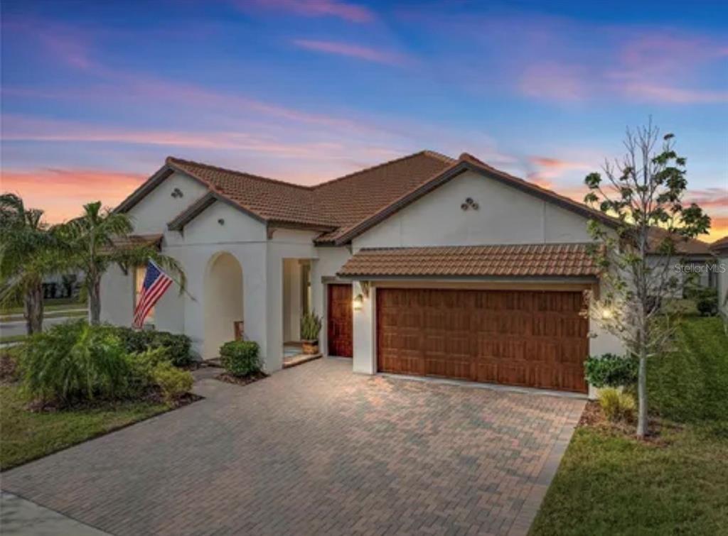 A single-story house with a tiled roof, a brick paver driveway, and a wooden garage door — 16959 SCUBA CREST STREET, WIMAUMA, FL