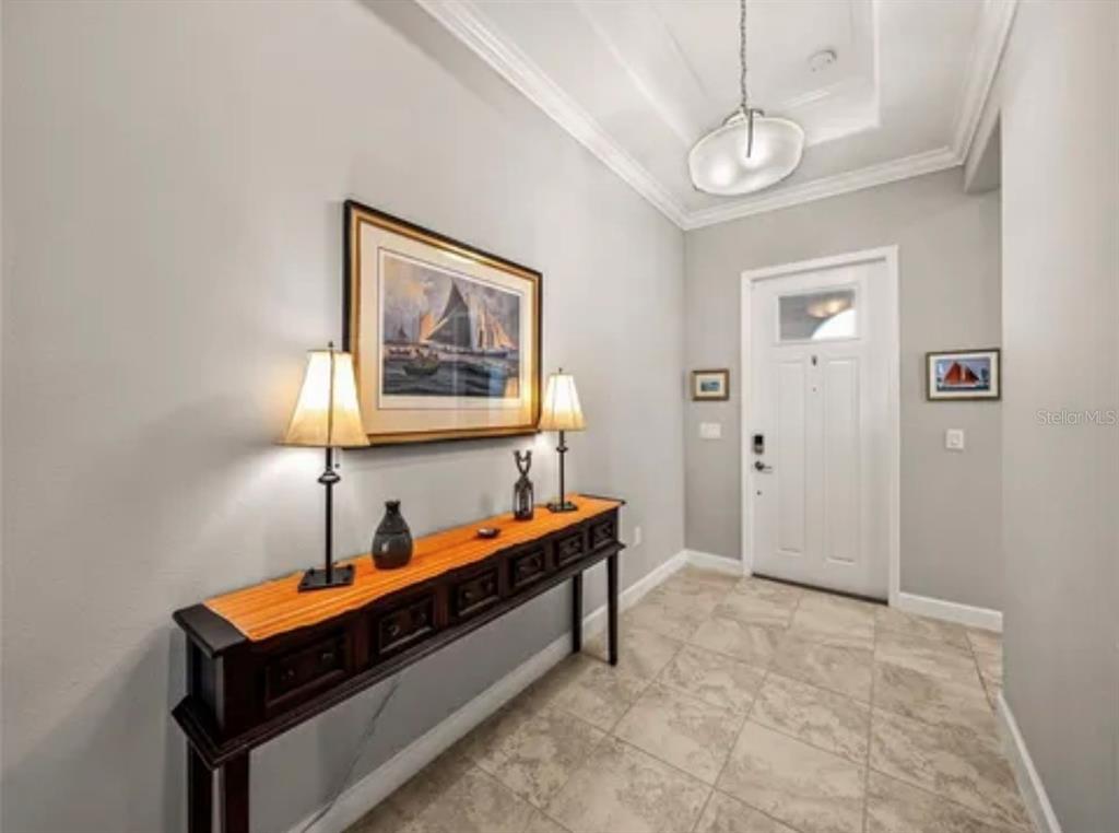 A foyer features a long console table, two lamps, wall art, and tile flooring — 16959 SCUBA CREST STREET, WIMAUMA, FL