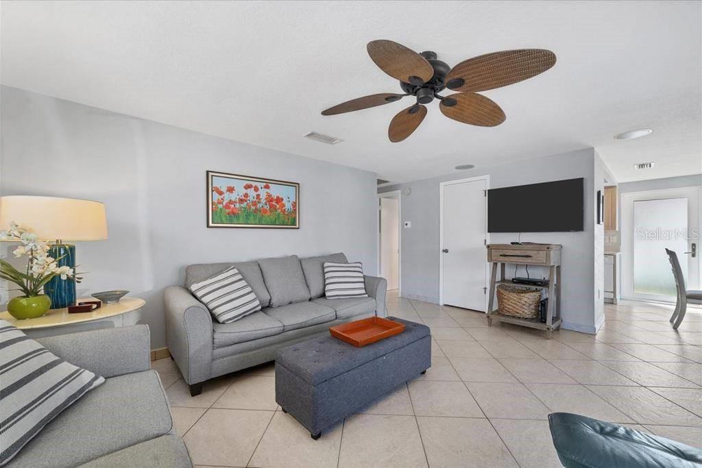 A living room features a gray sofa, a matching ottoman, and a ceiling fan — 6154 MIDNIGHT PASS ROAD UNIT B04, SARASOTA, FL