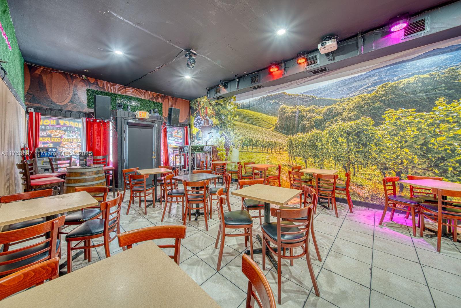 A restaurant dining area features tables, wooden chairs, and a large vineyard wall mural — HIGHLY PROFITABLE Restaurant-Bar For Sale on 8th St, Miami FL 33144, MIAMI, FL